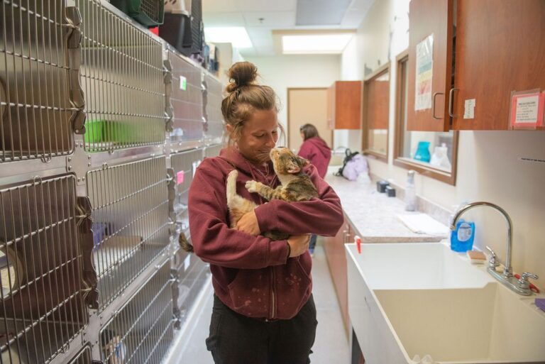 a woman holding a cat in a cage