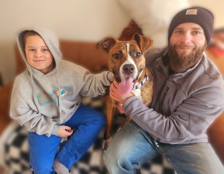 a man and boy sitting on a couch with a dog