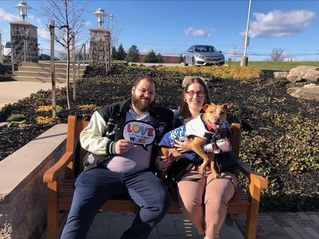 a man and woman sitting on a bench with a dog