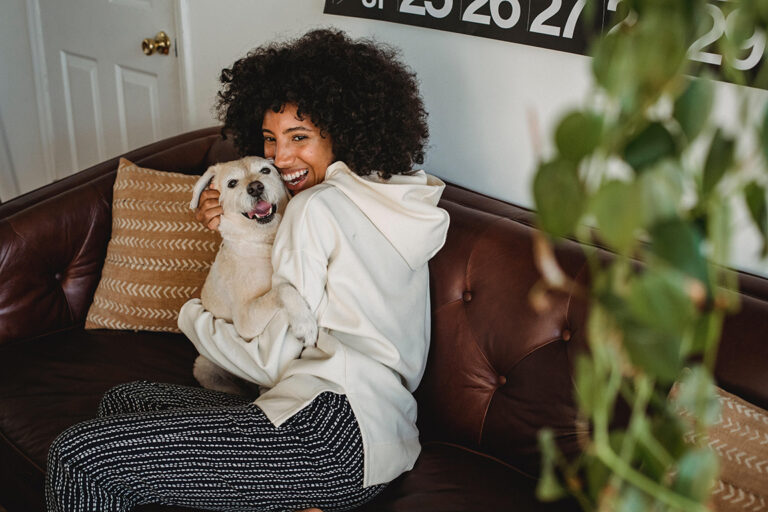 a woman sitting on a couch holding a dog