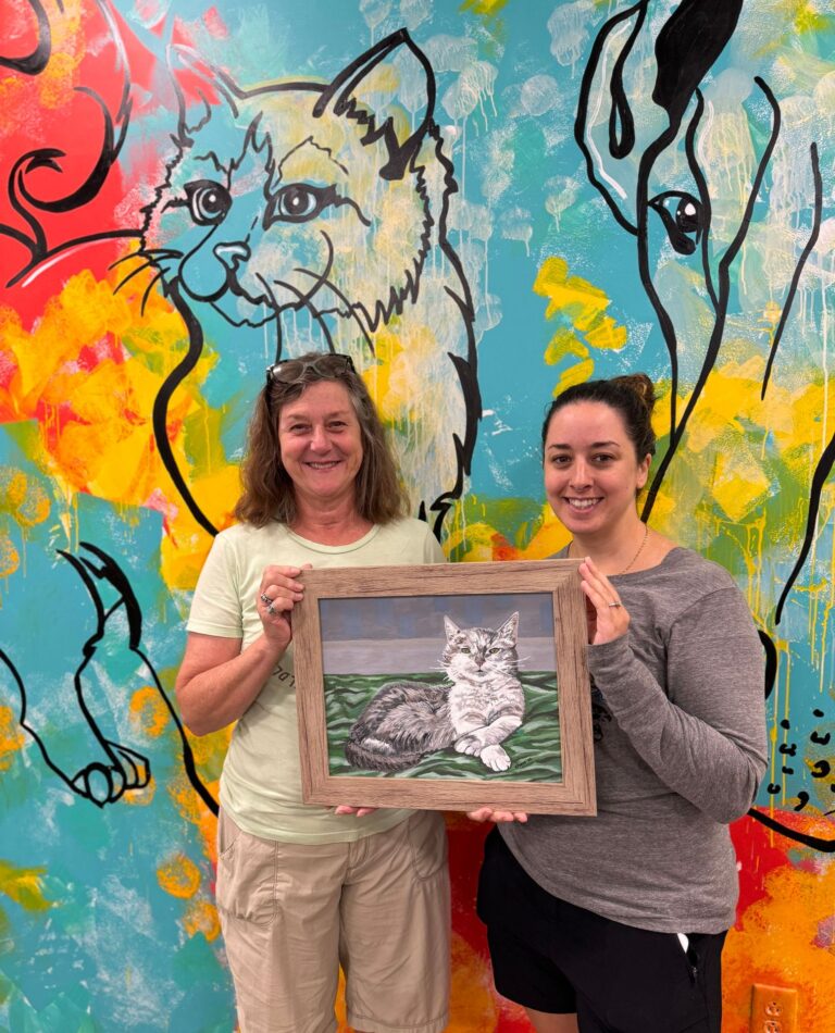 two women holding a picture of a cat