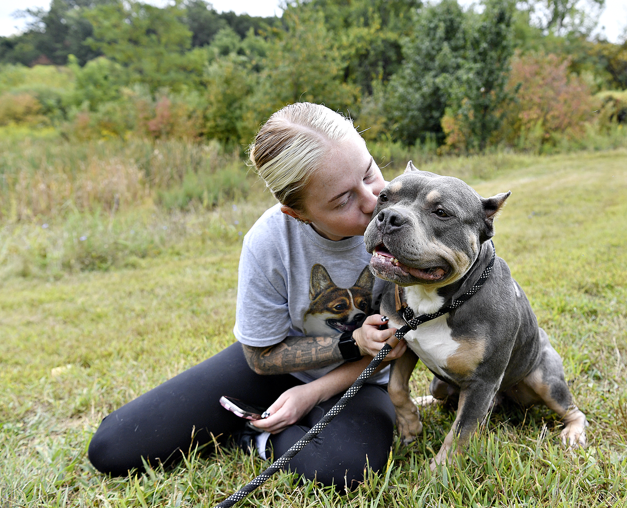 Person sitting with a dog outdoors.