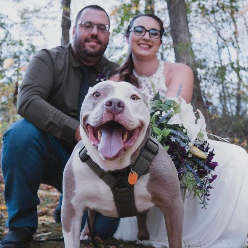 a man and woman posing for a picture with a dog